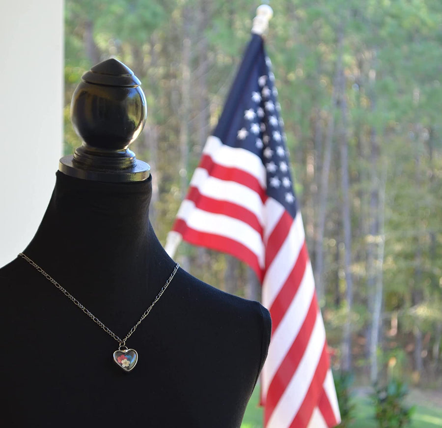 Handmade Red White and Blue Pressed Flower Heart Pendant Necklace on bust with flag in background. Truly Handmade in USA by Louisiana Artisan at Bayou Glass Arts Studio. Forget Me Nots