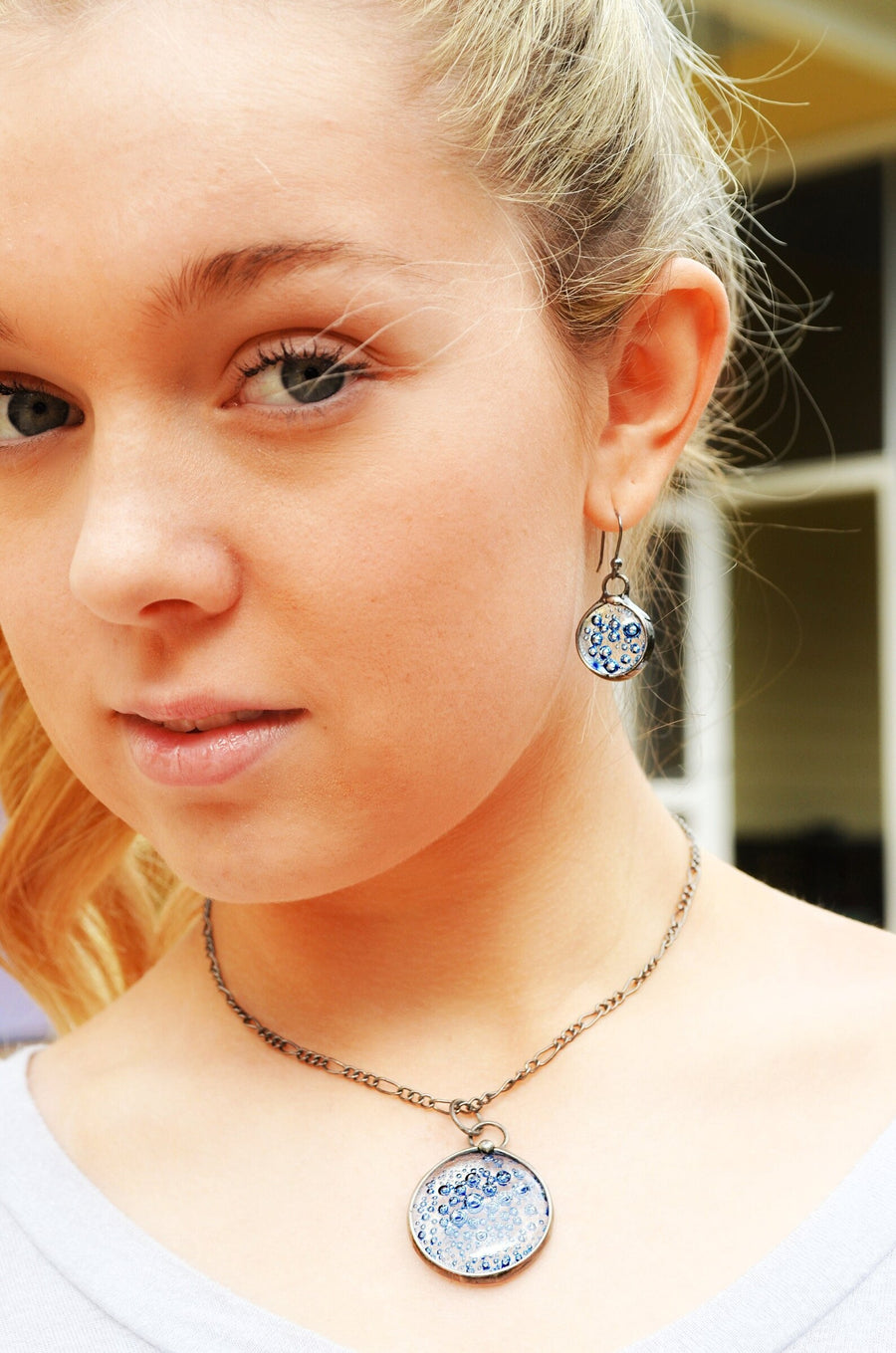Model wearing Blue Bubble Dangle earrings with hand formed sterling silver ear wires and Blue Bubble Dot Fused Glass Matching Necklace Pendant.