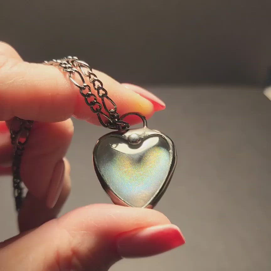 video of handmade iridescent white glass heart necklace with message hidden inside when held up to a light. This one says I Love You.See See Jewelry is hand made in USA by Louisiana Artisan at Bayou Glass Arts Studio. Secret message hidden inside is revealed when the pendant is held up to a light.