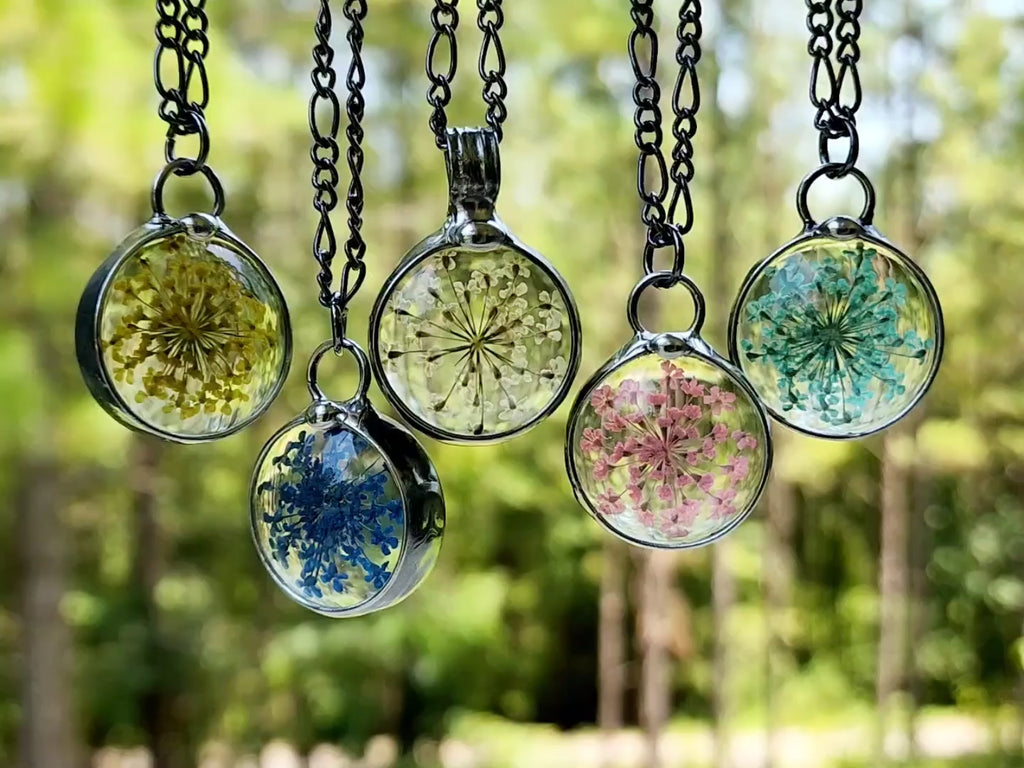 video of 5 different colored queen annes lace pendants. yellow blue natural pink aqua. Pressed Flower Jewelry  truly Hand Made in USA by Louisiana Artisan at Bayou Glass Arts Studio.