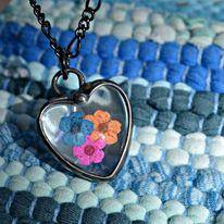 orange_blue_pink_flower_in_glass_heart_necklace_on_blue_background