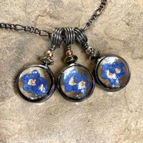 3 Dainty Forget Me Not Charms side by side, first has gold bead, next has copper bead and last one has silver bead. Real pressed flower Jewelry Hand Made in USA by Louisiana Artisan at Bayou Glass Arts Studio