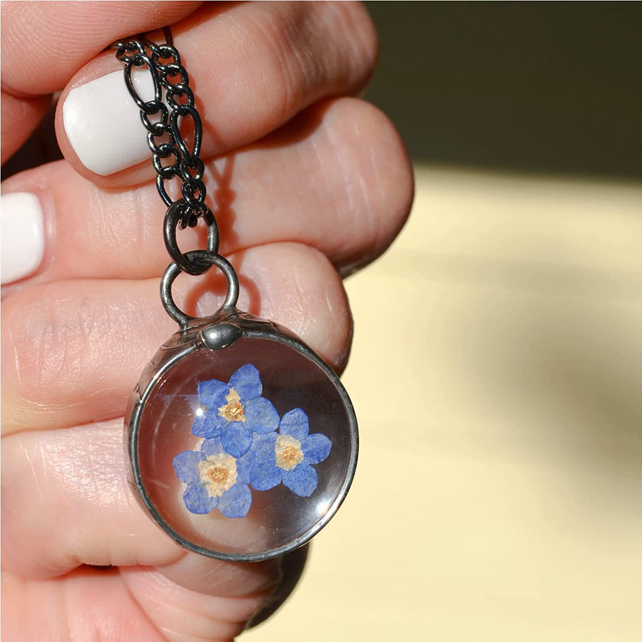 Handmade Pressed Flower Forget Me Not Pendant Necklace. 3 Blue Blooms grace this delicate pendant that is round and comes in gunmetal or shiny silver finish. All Jewelry is Hand Made in USA by Louisiana Artisan at Bayou Glass Arts Studio.