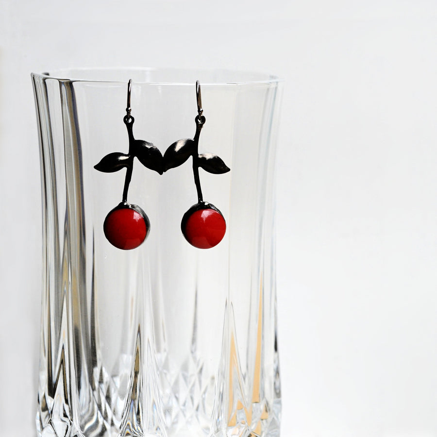 red_cherry_earrings_displayed_on_crystal_vase