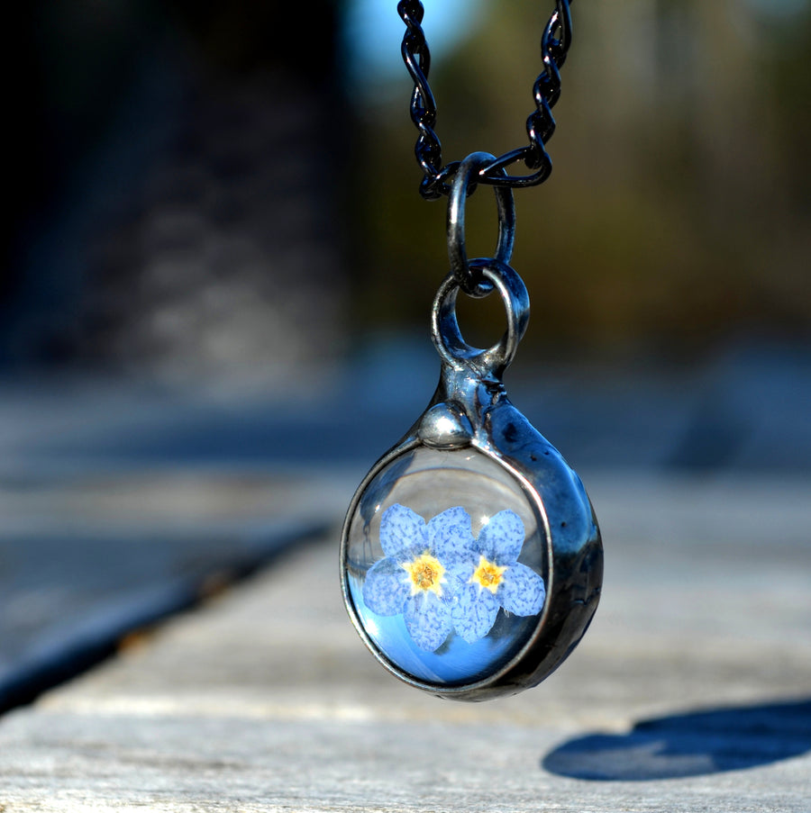 Forget me not necklace with 2 blue blooms inside round glass pendant, bezel is hand formed with copper and mixed silver solder by Louisiana Artisan. Hand made in USA