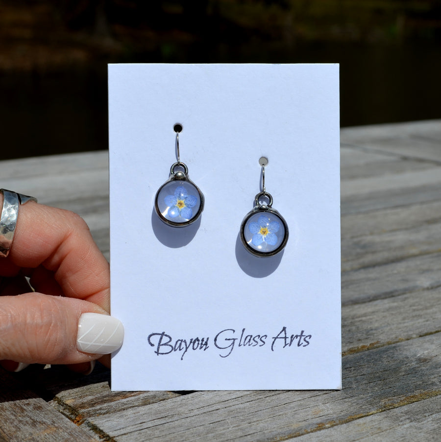 Forget me not earrings on sterling silver ear wires. One blue bloom inside each round glass earring, bezel is hand formed with copper and mixed silver solder by Louisiana Artisan. Hand made in USA