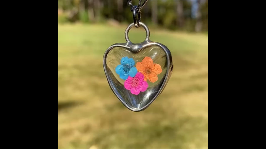 Video showing tri colored handmade forget me not heart pendant necklace for women. Multi colored tye dye look artisan metal crafted. Created in Louisiana USA with care.