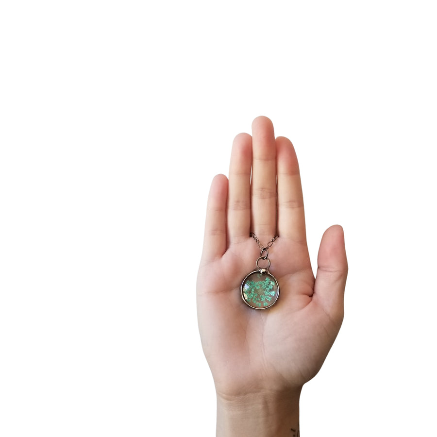 Palm of hand on white background holding turquoise queen annes lace pressed flower pendant. Truly Hand Made in USA by Louisiana Artisan at Bayou Glass Arts Studio. Chain is quality plated fully adjustable Figaro style. All are 100% handmade from metals that contain NO lead, cadmium, zinc or nickel. 