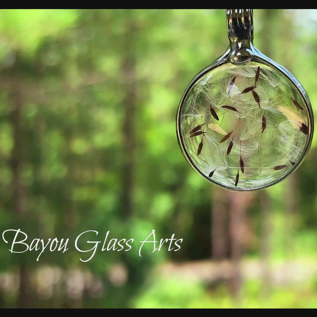Video of round shaped dandelion seed pendant necklace  filled with several dandelion seeds under glass. Truly hand made in USA by Louisiana Artisan.