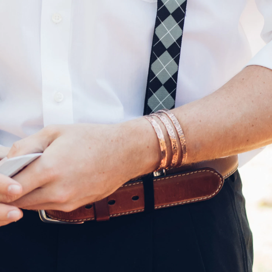 male model wearing 3 copper cuff bracelets, one of each. Full hand hammered, edge and bark. Each has a different look. Truly Hand made in Louisiana USA at Bayou Glass Arts Studio.