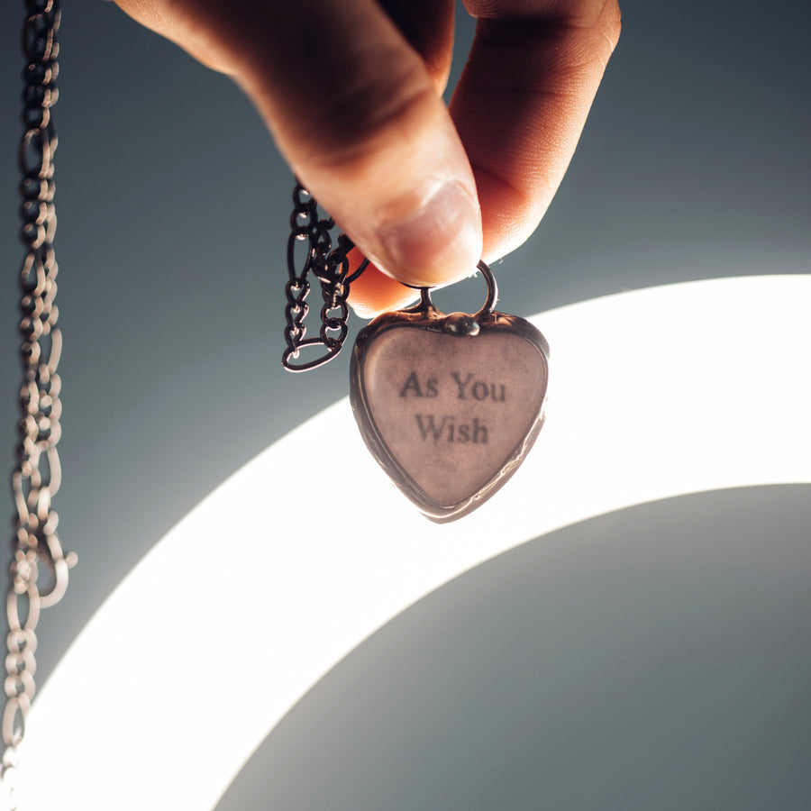 See See Heart Pendant Necklace being held up to bright light to reveal the hidden secret message words inside.See See Jewelry is hand made in USA by Louisiana Artisan at Bayou Glass Arts Studio. Secret message hidden inside is revealed when pendant is held up to a light.