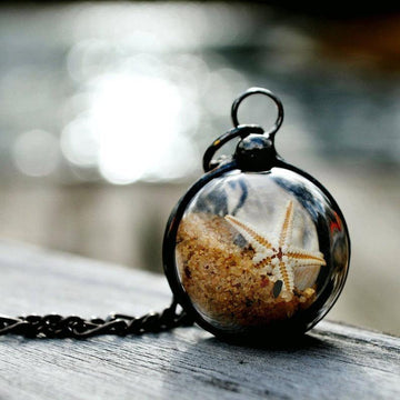 Beach Terrarium Orb Necklace filled with starfish sand and shells. One side is magnified. Loose items create this shaker pendant. Truly Hand Made in USA by Louisiana Artisan at Bayou Glass Arts. Great gift for Mom wife girlfriend grandmother sister Christmas Birthday